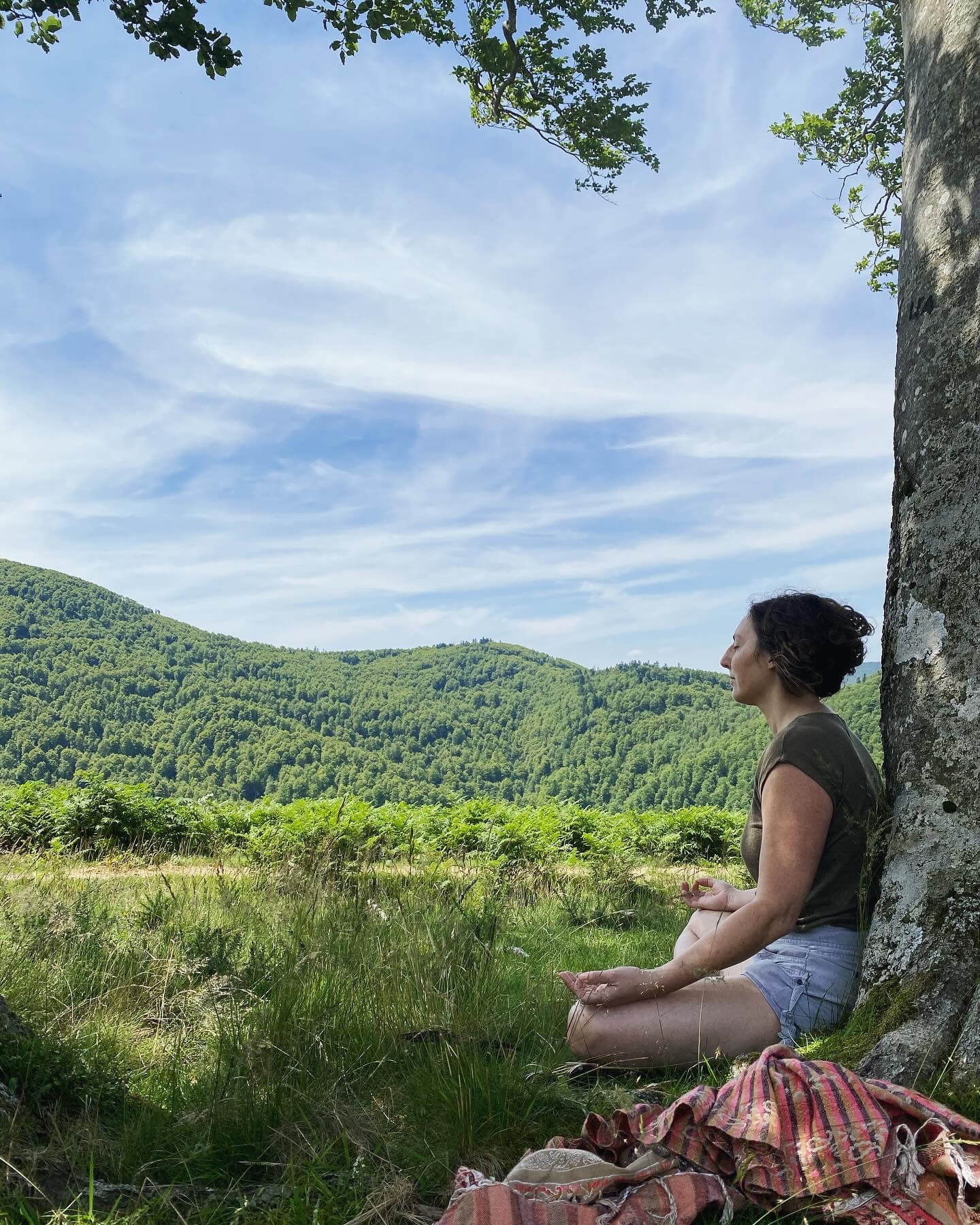Femme médite contre un arbre